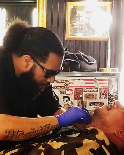 Barber Allen sculpting beard with straight razor at The Mane Den Barber Shop